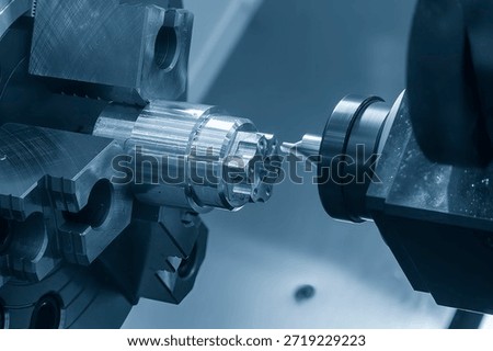 The CNC lathe machine drilling process on metal shaft parts by center drill tool in the blue tone. The high technology metal working with CNC turning machine.