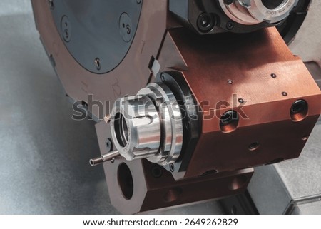 CNC Machine with a brown casing and a silver part.  machine is used for drilling. machine has a small hole in the middle