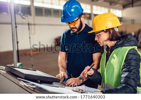 CNC Machine Operator and industrial engineer typing fabrication program for cutting