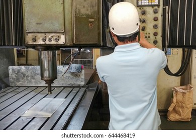 The CNC machine operator operate the old double column  CNC machine with safety hat. CNC machine operation concept 