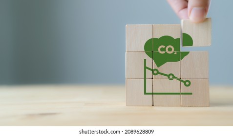 CO2 emission concept. Green industries business concept. Net zero emissions. Renewable energy, sustainable technology, ecology solutions. Hand puts the wooden cubes with CO2 emission reduction icon. 