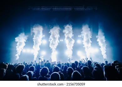Co2 flame and silhouette of crowd at a music festival in front of bright stage lights