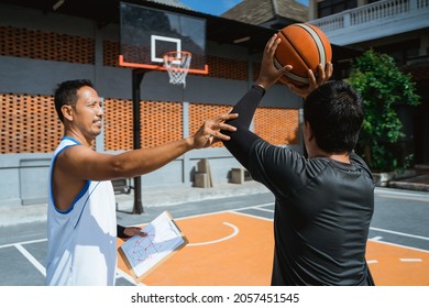 a coach advises a male basketball player to shoot the ball in the hoop - Powered by Shutterstock