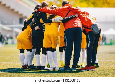 Coach Coaching Girls Sports Team. Girls School Sports Team Huddling With Coach On The Grass Field. Soccer Football Junior Girls Team At Sports Outdoor Field Before Match. Coach Building Confidence