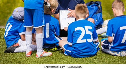 Coach Coaching Kids Soccer Team. Youth Football Team with Coach at the Soccer Stadium. Boys Listening to Coach's Instructions Before Competition. Coach Giving Team Talk Using Soccer Tactics Board - Powered by Shutterstock