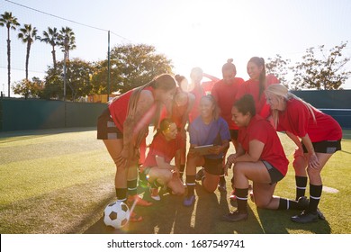 Coach With Digital Tablet Discussing Tactics With Womens Football Team Training For Soccer Match