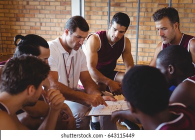 Coach explaining game plan to basketball players in the court - Powered by Shutterstock