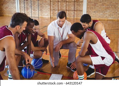 Coach Explaining Game Plan To Basketball Players In The Court