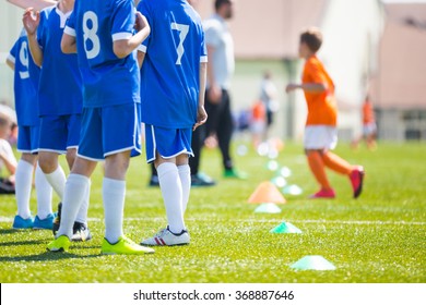 Coach Giving Children Soccer Team Instructions. Young Boys And Soccer Coach Watching Football Match. Youth Reserve Players Ready To Play Football Tournament