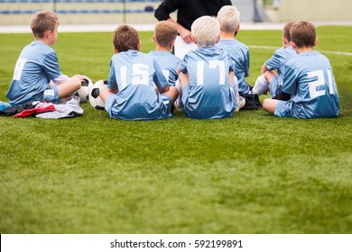 Coach Giving Young Soccer Team Instructions. Youth Football Team Listening Coach Briefing. Coaching Kids Soccer Team. Youth Sports Background