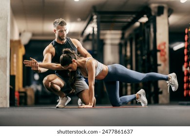 Coach is helping fit strong sportswoman with bird dog workout in a gym. - Powered by Shutterstock