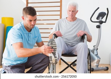 Coach helping invalid senior in fitness studio - Powered by Shutterstock