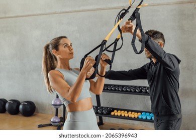 Coach Helps Concentrated Woman With Suspension Strap Workout At Gym Hiit Class.