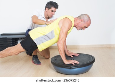 Coach Helps Senior With Bosu Exercise