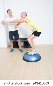 Coach Helps Senior With Bosu Exercise