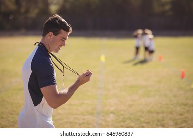 Coach Holding Stopwatch In Park During Competition