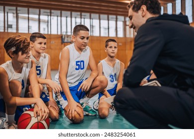 The coach interacts with young basketball players, discussing game tactics and fostering a sense of sport teamwork - Powered by Shutterstock