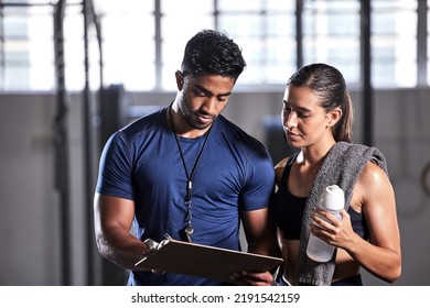 Coach planning workout, schedule and training with athlete for active, fitness and wellness in a gym. Trainer writing notes for sports client with routine to gain toned, strong and fit body muscle - Powered by Shutterstock