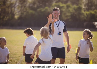 Coach and schoolgirl giving high five to each other during competition in park - Powered by Shutterstock