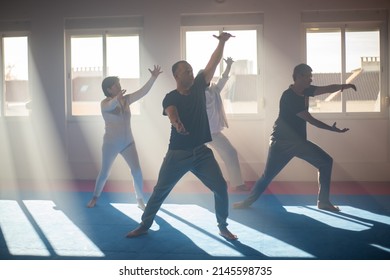 Coach Showing Tai Chi Exercise To Students. Male Trainer Standing In Front Of Senior People And Moving Arms At Grou Class. Martial Art Concept