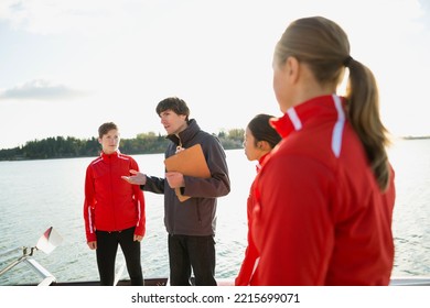 Coach talking to rowing team at waterfront - Powered by Shutterstock