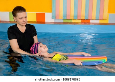 Coach Teaching Kid In Indoor Swimming Pool How To Swim With Flutter Board