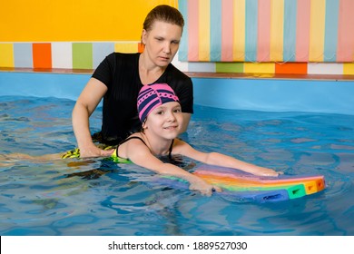 Coach Teaching Kid In Indoor Swimming Pool How To Swim With Flutter Board