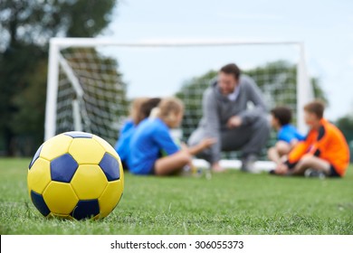 Coach  And Team Discussing Soccer Tactics With Ball In Foreground - Powered by Shutterstock