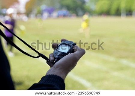 The coach timed the finish line with a stopwatch to determine the winner of the school sports day running event. soft and selective focus.                               
