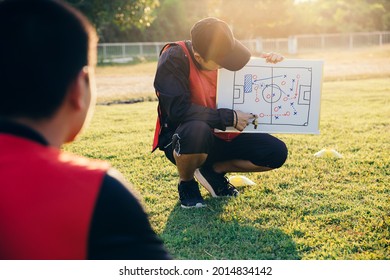 Coach training a tactic for asian teenager football player.