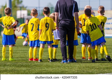 Coach And Youth Soccer Reserve Players Watching Football Match. Coach Giving Young Soccer Team Instructions.  Coach Briefing. Soccer Football Background.