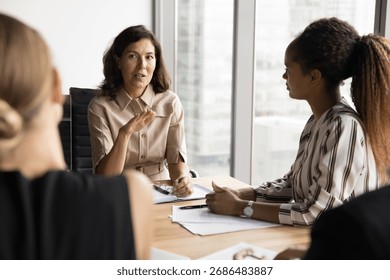 Coaching session. Confident mid aged female mentor trainer coach lead group discussion on seminar for diverse young interns workmates team give advice on business strategy guide in professional growth