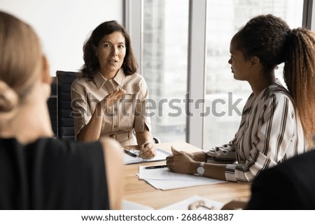 Coaching session. Confident mid aged female mentor trainer coach lead group discussion on seminar for diverse young interns workmates team give advice on business strategy guide in professional growth