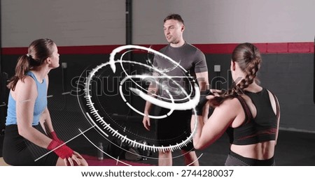 Coaching standing man in fitted gray t-shirt directing two women at gym with red mat, HUD. Trainer, studio, fitness, group, leadership, padding, flooring