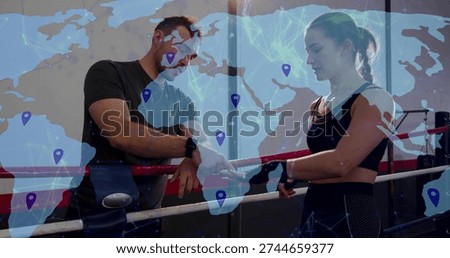 Coaching trainer pointing at boxer wrapped hands in gymwear in boxing ring, with world map overlay. Athlete, coach, gym, fitness, digital, locations, markers