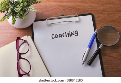 Coaching word on paper with glass ballpen and green plant