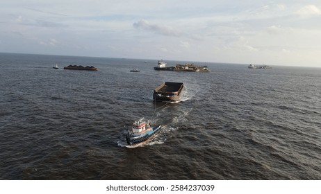 Coal barge loading operation using a floating crane to vessel in open waters off Banjarmasin, Indonesia.