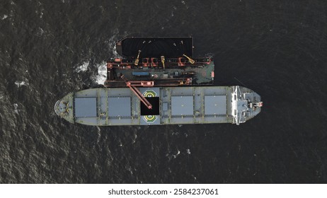 Coal barge loading operation using a floating crane to vessel in open waters off Banjarmasin, Indonesia.