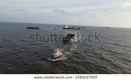 Coal barge loading operation using a floating crane to vessel in open waters off Banjarmasin, Indonesia.