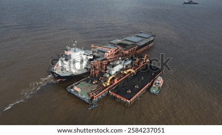 Coal barge loading operation using a floating crane to vessel in open waters off Banjarmasin, Indonesia.