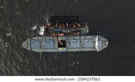 Coal barge loading operation using a floating crane to vessel in open waters off Banjarmasin, Indonesia.