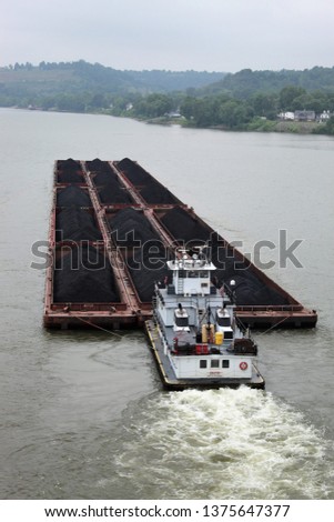 A coal carrying barge traveling down the Ohio river past Marietta Ohio as seen from the Williamstown WVa. bridge