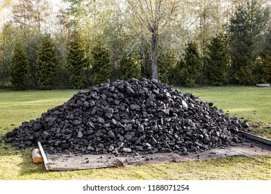 Coal Is A Combustible Black Or Brownish-black Sedimentary Rock. Pit Coal Is Extracted From Earth. Pile Of Coal On Green Grass In Home Garden.