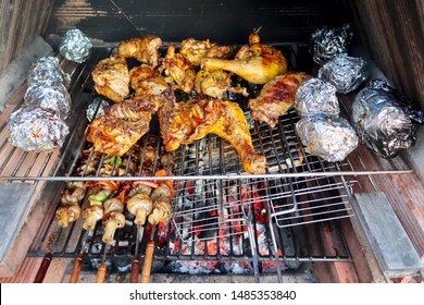 Coal Fire Bbq Grill With Tasty Barbecue Chicken, Aluminium Foil Baking Potatoes And Vegetables Cooking In Marbella, Spain                                