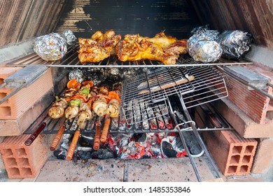 Coal Fire Bbq Grill With Tasty Barbecue Chicken, Aluminium Foil Baking Potatoes And Vegetables Cooking In Marbella, Spain                                