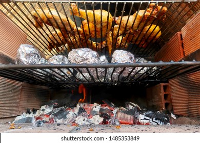 Coal Fire Bbq Grill With Tasty Barbecue Chicken, Aluminium Foil Baking Potatoes And Vegetables Cooking In Marbella, Spain                                