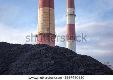 Coal heap, natural black coal with industrial chimney. Industrial landscape with pile of carbon material. Global warming, CO2 emission, coal energy issues. Coal mine in Katowice, Poland.