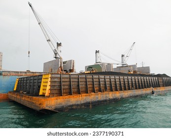 Coal loading and unloading activities at sea from barges to large ships.
