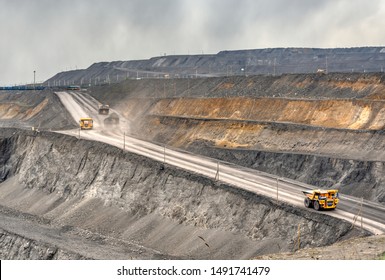 Coal Mine, Aerial View. Road For The Movement Of Mining Trucks. Ways To Transport Minerals To The Surface Of The Earth. A Mining Truck Is Driving Along A Mountain Road.