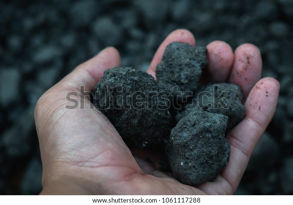 Coal miner in the man hands of coal\
background. Industrial coals. Volcanic\
rock.